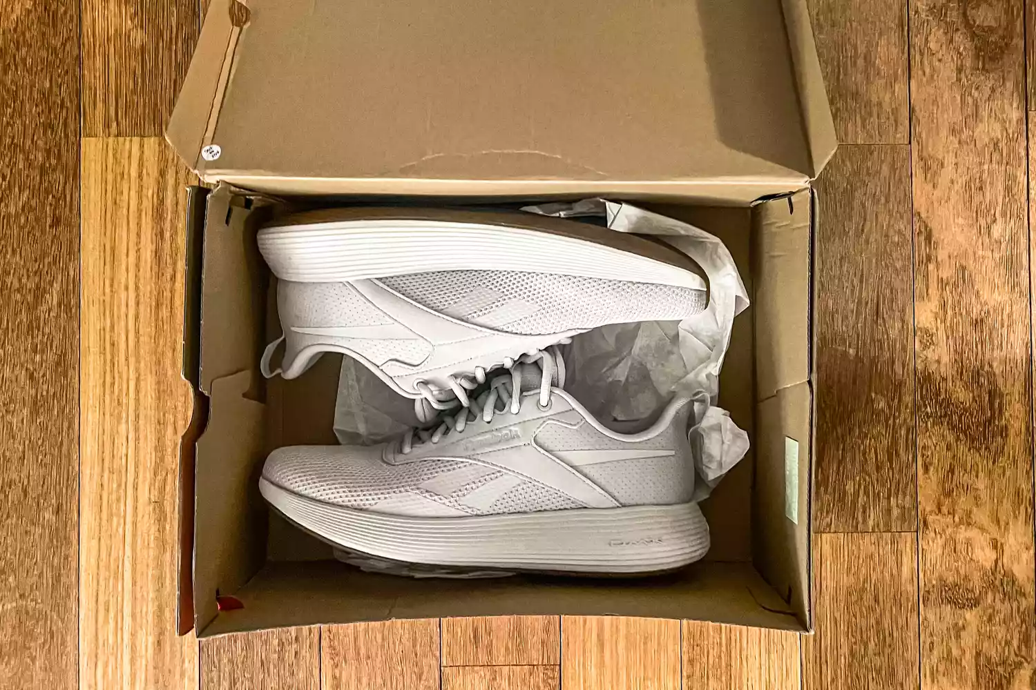 A pair of Reebok Unisex DMX Comfort+ Walking Shoes inside a shoebox