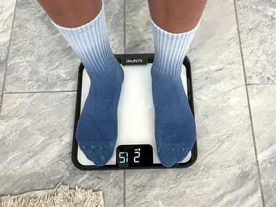 A person stands on the Renpho R-MSB02 Elis Chroma Aspire Smart Scale in socks