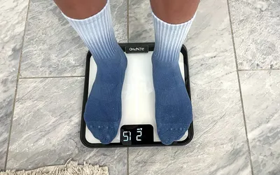 A person stands on the Renpho R-MSB02 Elis Chroma Aspire Smart Scale in socks