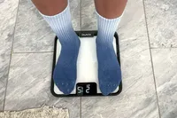 A person stands on the Renpho R-MSB02 Elis Chroma Aspire Smart Scale in socks