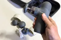 A person holds up the Renpho Mini Thermal Massage Gun