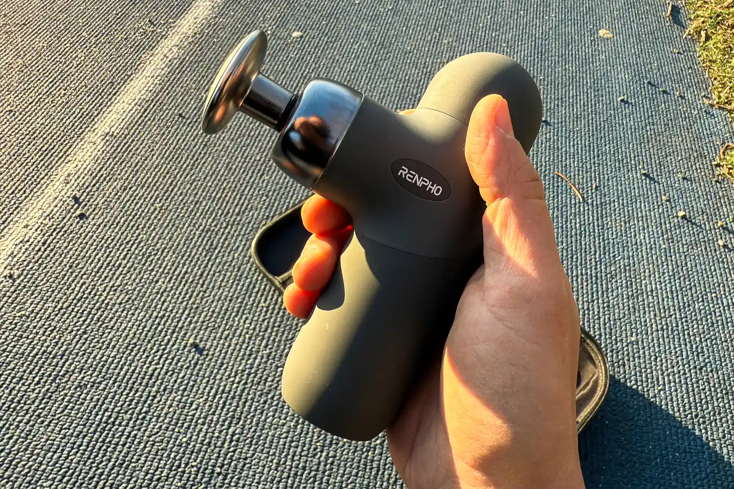 A person holds up the Renpho Mini Thermal Massage Gun