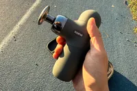 A person holds up the Renpho Mini Thermal Massage Gun