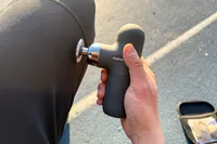 A person uses the Renpho Mini Thermal Massage Gun on their knee
