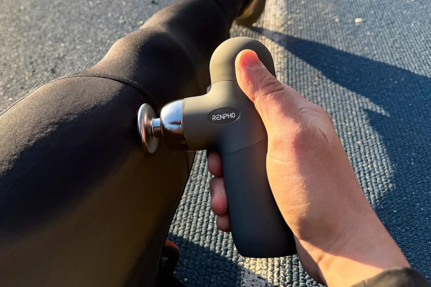 A person uses the Renpho Mini Thermal Massage Gun on their leg