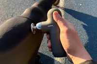 A person uses the Renpho Mini Thermal Massage Gun on their leg