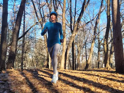 Woman running on trail in the woods wearing NNew Balance Fresh Foam X 1080v12
