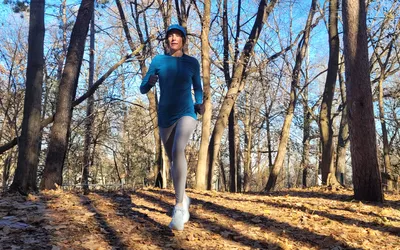 Woman running on trail in the woods wearing NNew Balance Fresh Foam X 1080v12
