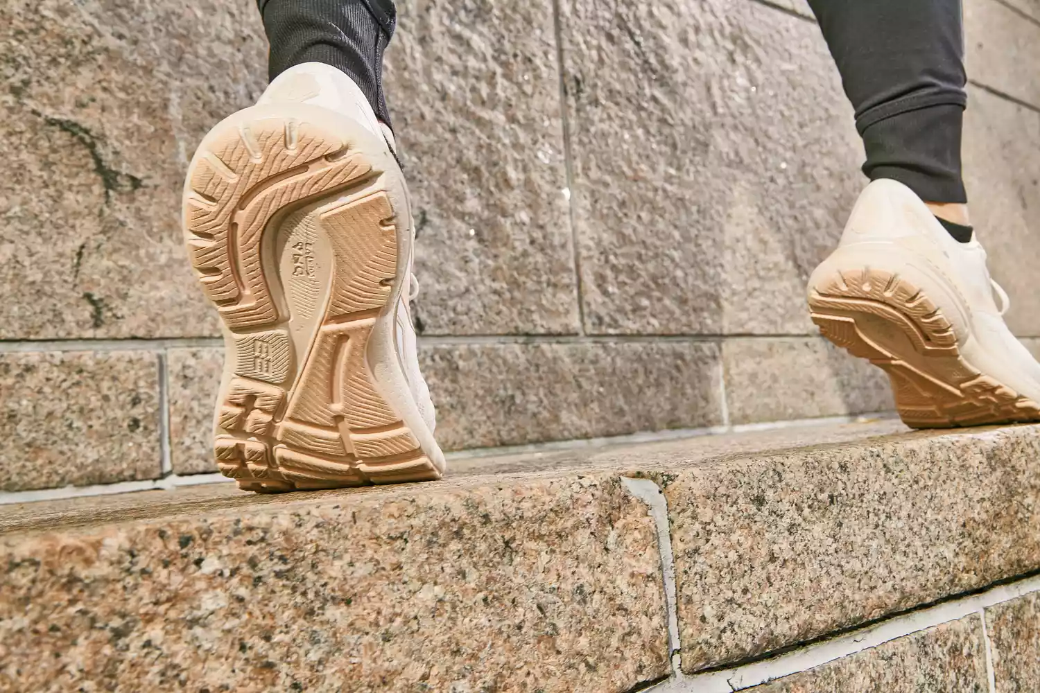 A close up of the sole of the Brooks Adrenaline GTS 23 on feet walking on stone surface