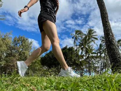 A person runs outside in grass while wearing the Brooks Women's Ghost 16 Running Shoes
