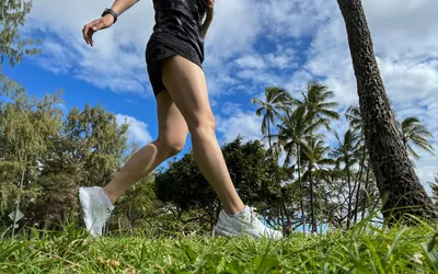 A person runs outside in grass while wearing the Brooks Women's Ghost 16 Running Shoes