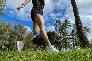 A person runs outside in grass while wearing the Brooks Women's Ghost 16 Running Shoes