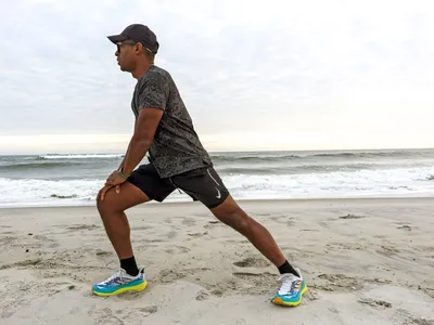 A person stretching on a beach while wearing Hoka Women's Stinson 7