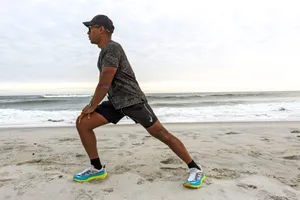 A person stretching on a beach while wearing Hoka Women's Stinson 7
