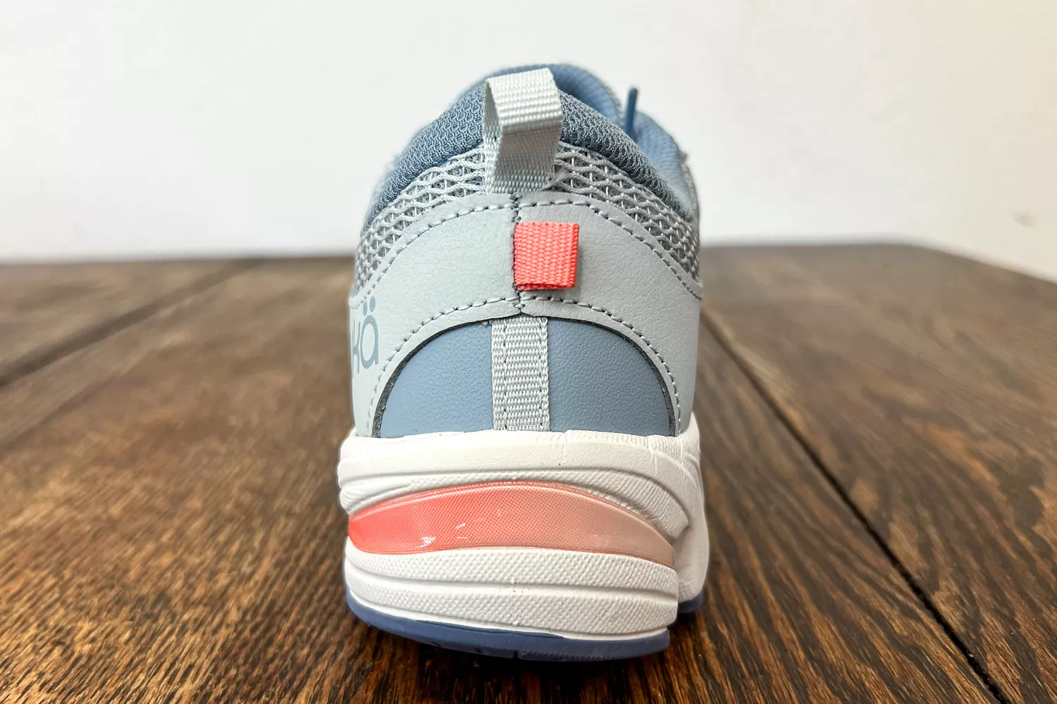 A Ryka Women's Invoke Walking Shoe from the back on a wooden surface
