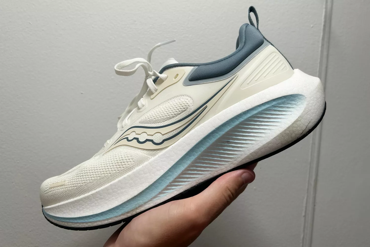 A person holds up the Saucony Men's Surge 3 Everyday Shoe