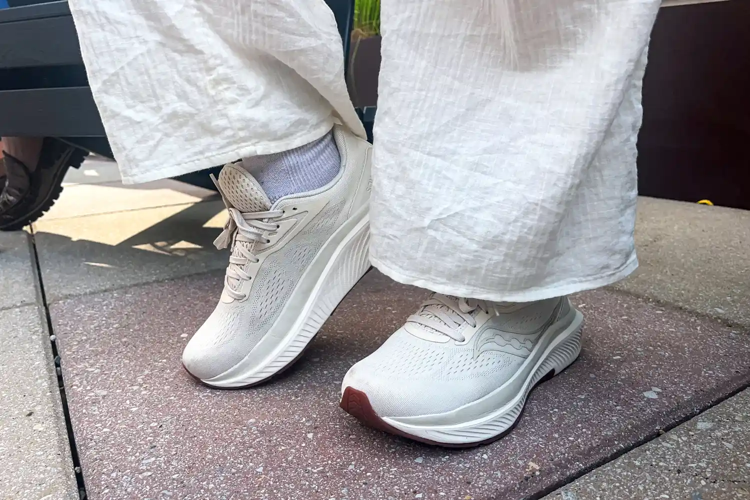 A person wears the Saucony Women's Echelon 10 Running Shoes while walking on stone