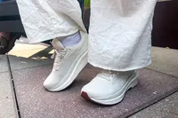 A person wears the Saucony Women's Echelon 10 Running Shoes while walking on stone