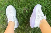 Two feet wearing the Saucony Women's Guide 18 Sneakers on grass