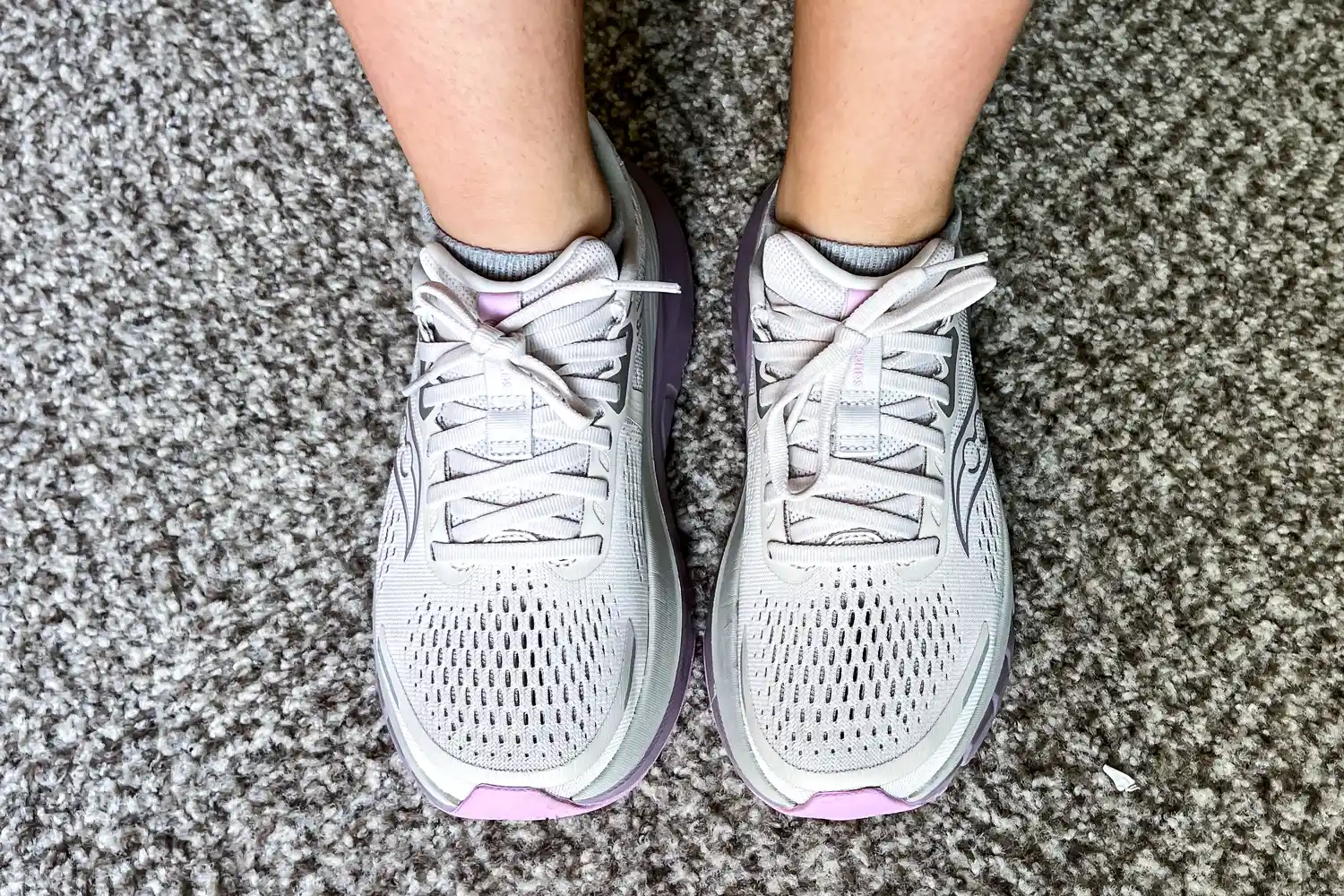 A person wears the Saucony Women's Guide 18 Sneakers on carpet