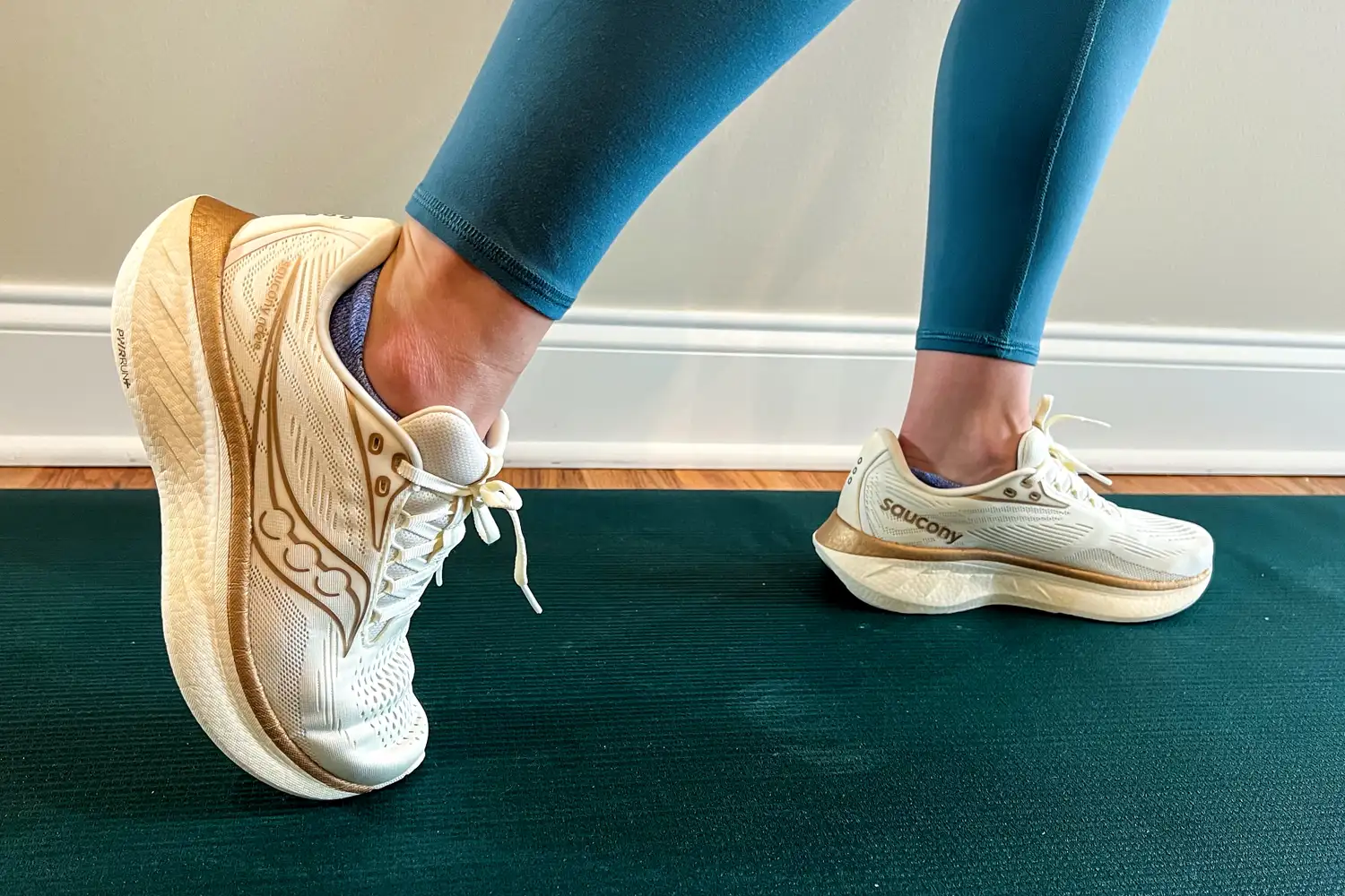 Person wearing Saucony running shoes performing a lunge on a green yoga mat