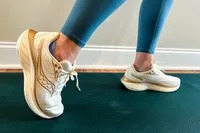 Person wearing Saucony running shoes performing a lunge on a green yoga mat