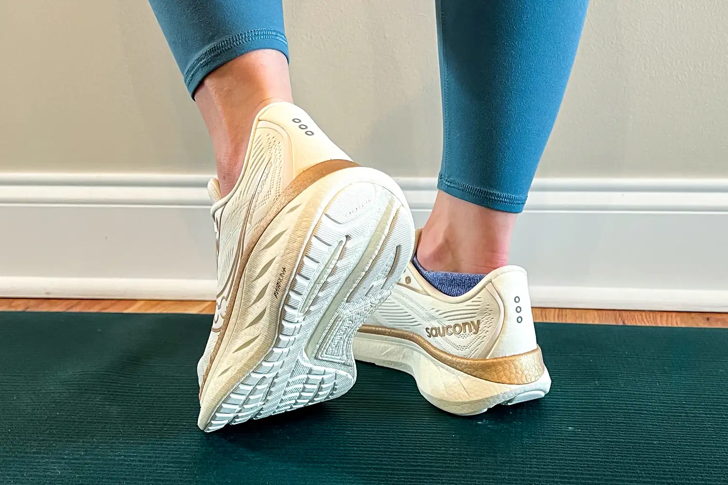 Person wearing Saucony sneakers standing on a green mat