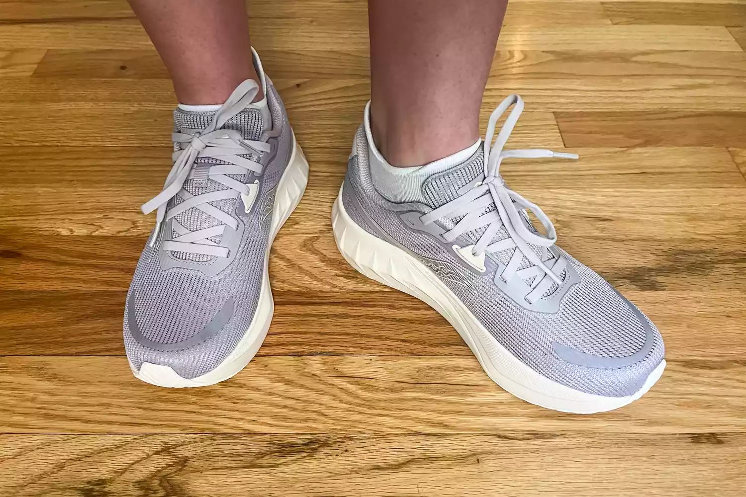 A person wears the Saucony Women's Tide 2 Walking Shoes on a hardwood floor