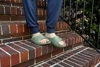 Feet wearing Oofos OoAhh Slide Sandals on brick steps