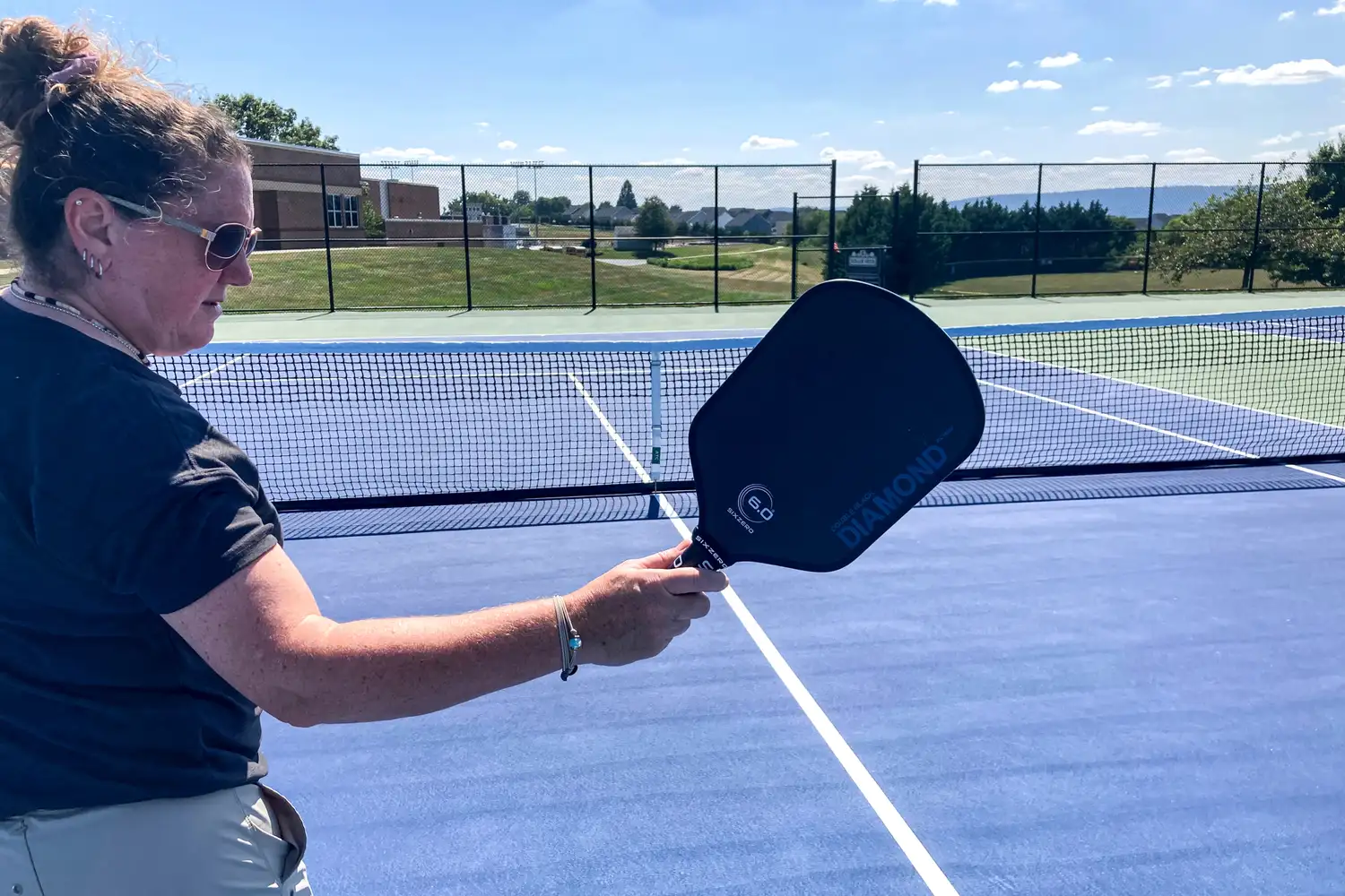 A person holds up the Six Zero Double Black Diamond Control Pickleball Paddle
