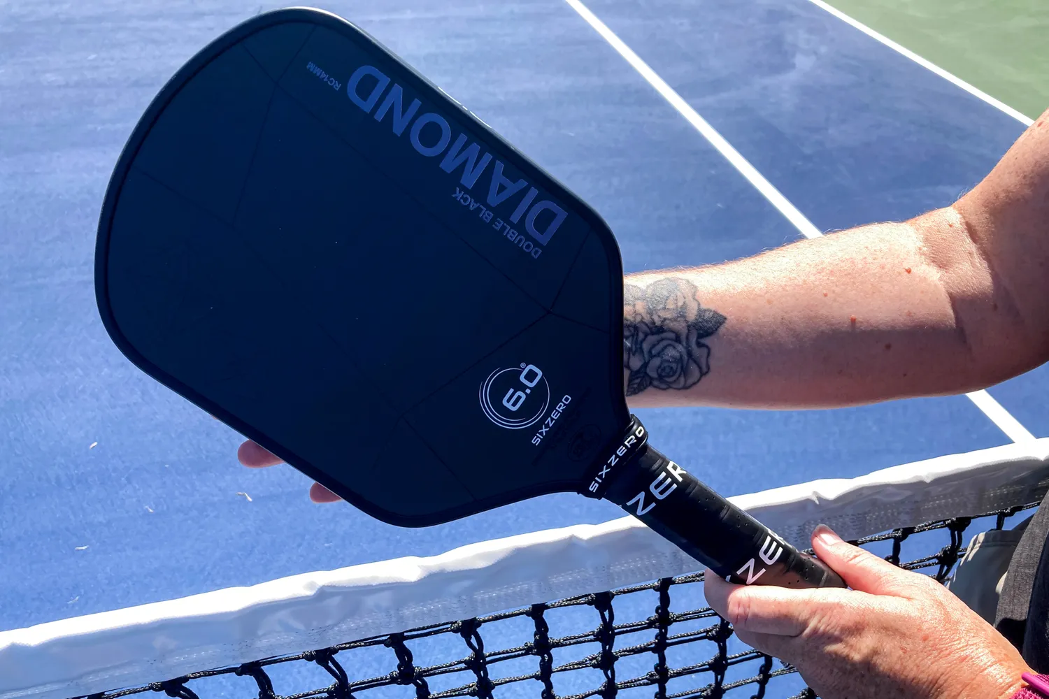 A person holds up the Six Zero Double Black Diamond Control Pickleball Paddle