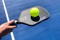 A person balances a pickleball on the Six Zero Double Black Diamond Control Pickleball Paddle