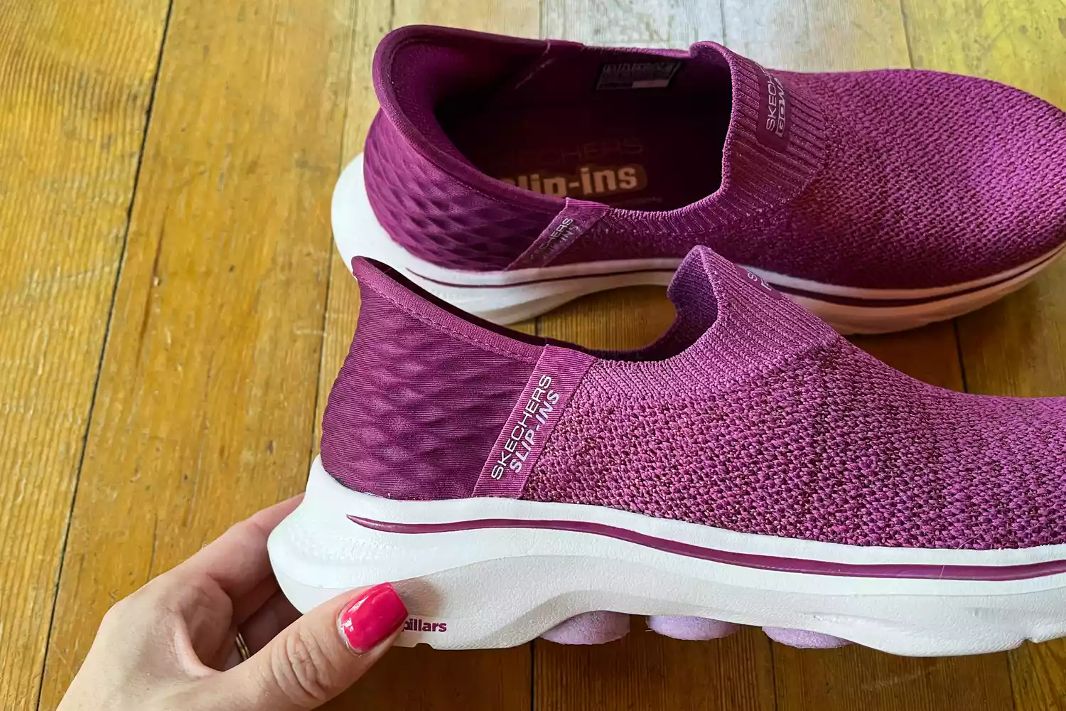 A person holds up the Skechers Slip-Ins Go Walk 7 Springtime Walking Shoe