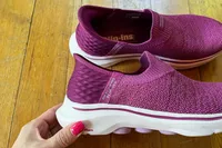 A person holds up the Skechers Slip-Ins Go Walk 7 Springtime Walking Shoe