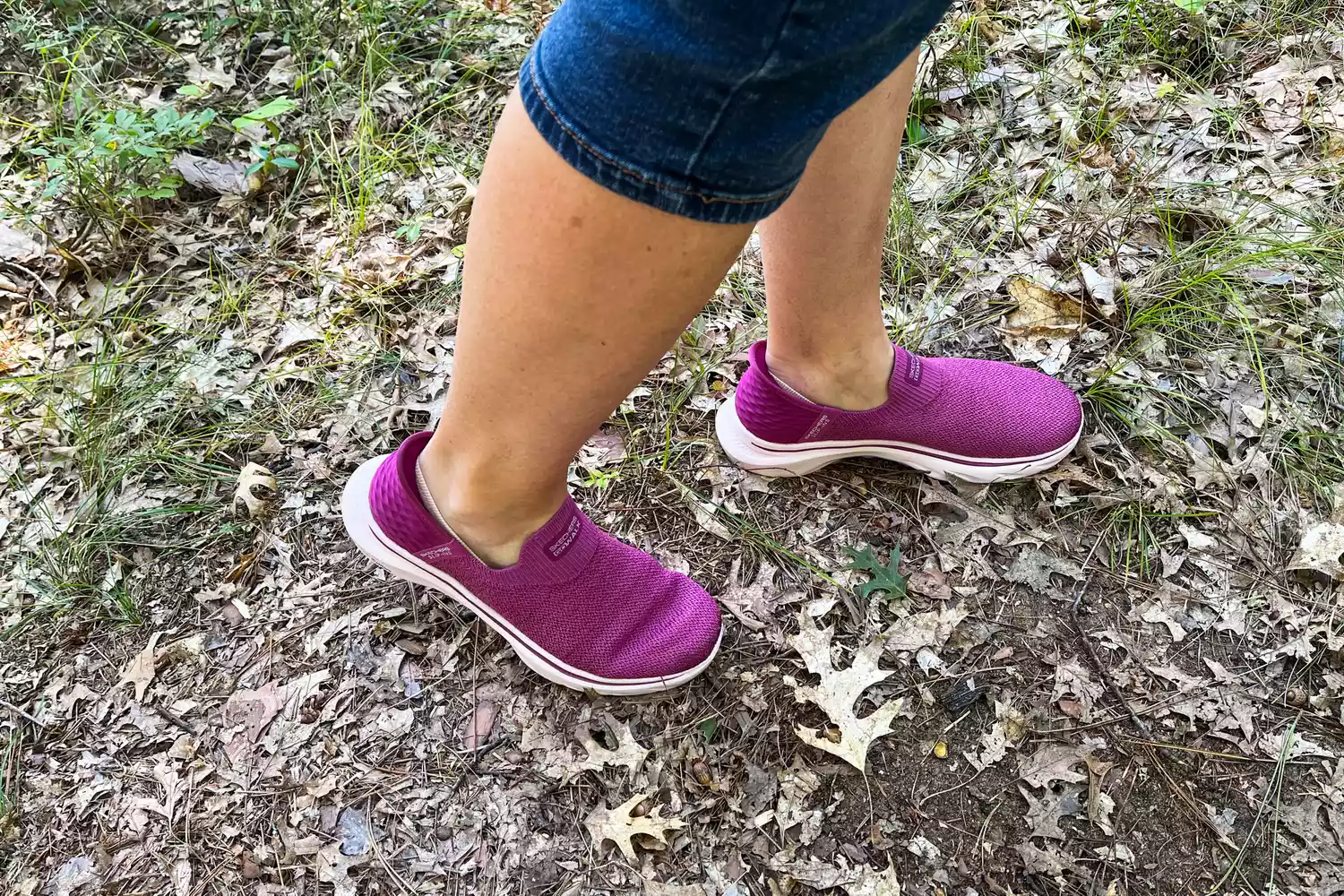 A person walks outside in leaves while wearing the Skechers Slip-Ins Go Walk 7 Springtime Walking Shoes