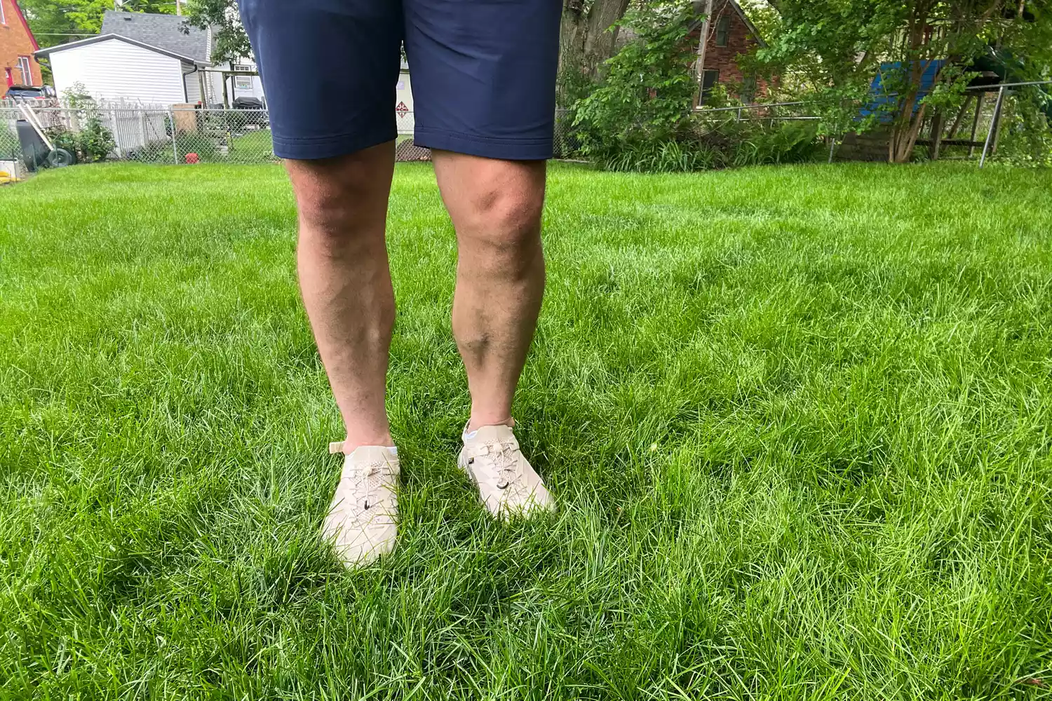 A person stands in grass while wearing the Hoka Men's Hopara 2 Sandals