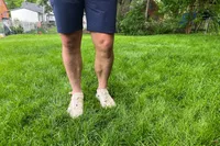 A person stands in grass while wearing the Hoka Men's Hopara 2 Sandals