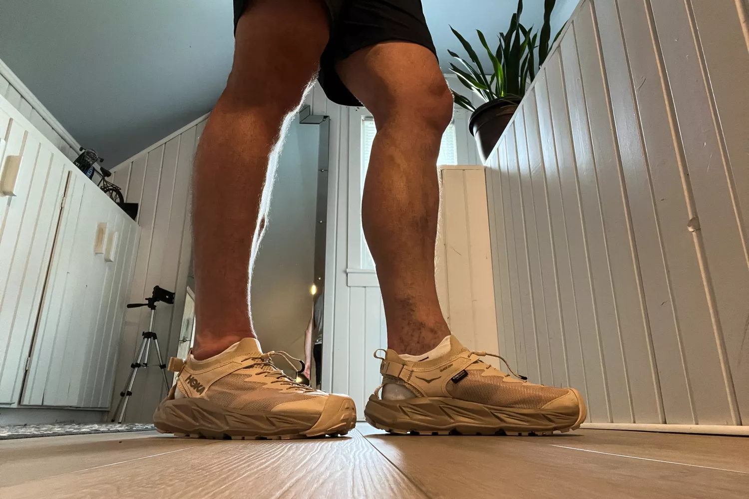 A person stands inside while wearing the Hoka Men's Hopara 2 Sandals