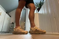 A person stands inside while wearing the Hoka Men's Hopara 2 Sandals