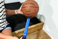 A person pumps air into the Spalding Rookie Gear Youth Indoor-Outdoor Basketball