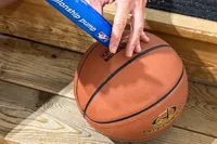 A person pumps air into the Spalding Rookie Gear Youth Indoor-Outdoor Basketball