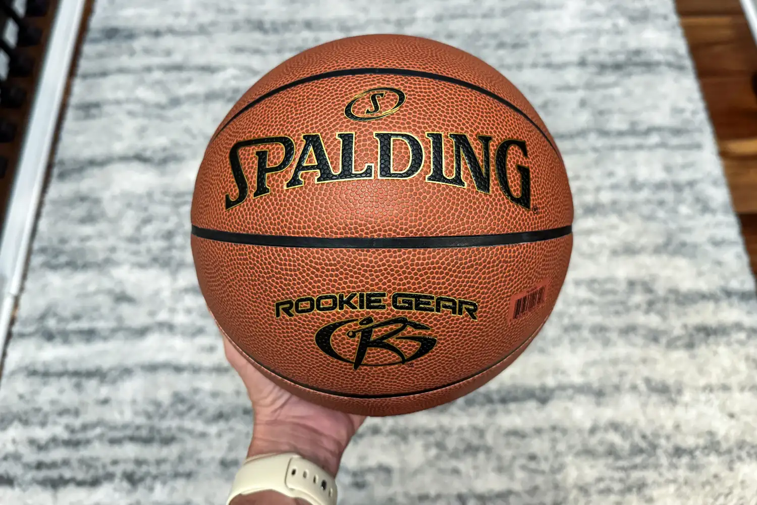 A person holds up the Spalding Rookie Gear Youth Indoor-Outdoor Basketball