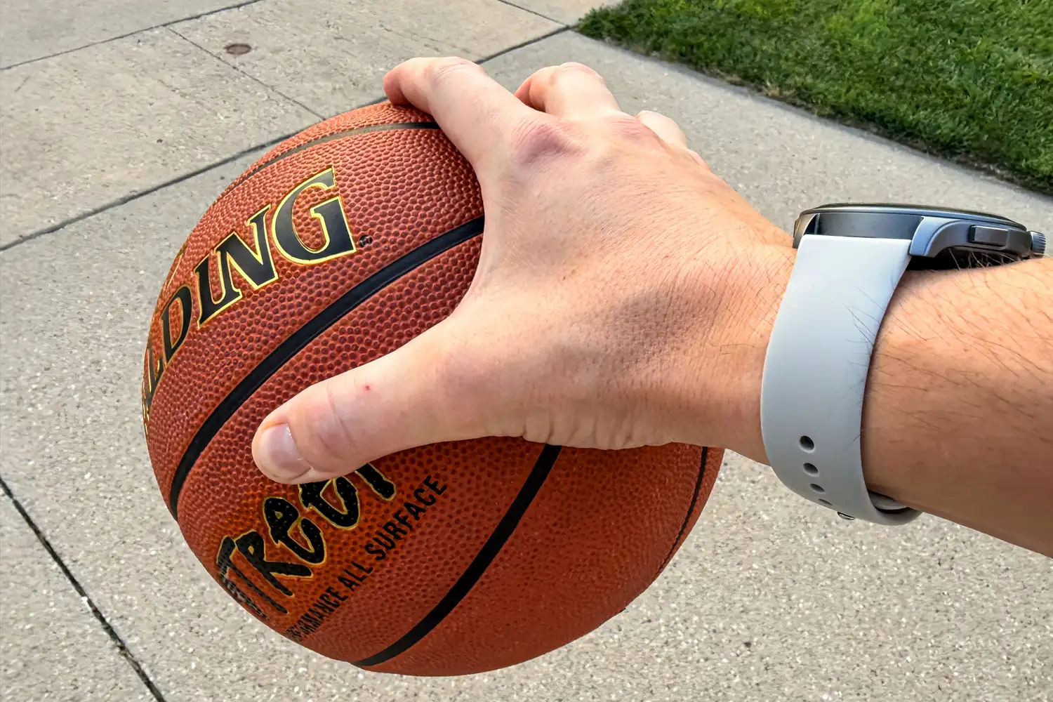 A person palms the Spalding Street Outdoor Basketball