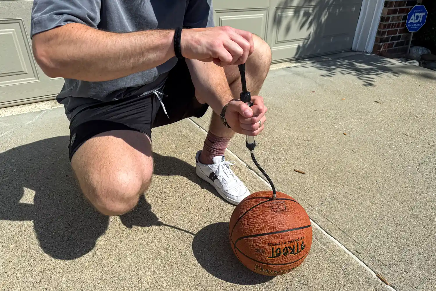 A person pumps air into the Spalding Street Outdoor Basketball