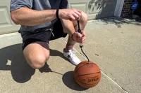 A person pumps air into the Spalding Street Outdoor Basketball