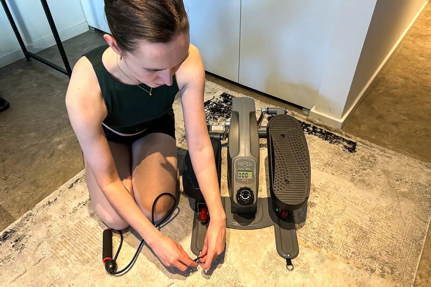 A person assembles the Sunny Health & Fitness Smart Stand/Sit Mini Elliptical Exercise Trainer