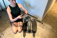 A person examines the handle on the Sunny Health & Fitness Smart Stand/Sit Mini Elliptical Exercise Trainer arm strap