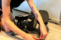 A person assembles the Sunny Health & Fitness Smart Stand/Sit Mini Elliptical Exercise Trainer