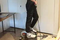 A person uses the arm bands on the Sunny Health & Fitness Smart Stand/Sit Mini Elliptical Exercise Trainer