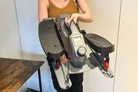 A person lifts up the Sunny Health & Fitness Smart Stand/Sit Mini Elliptical Exercise Trainer